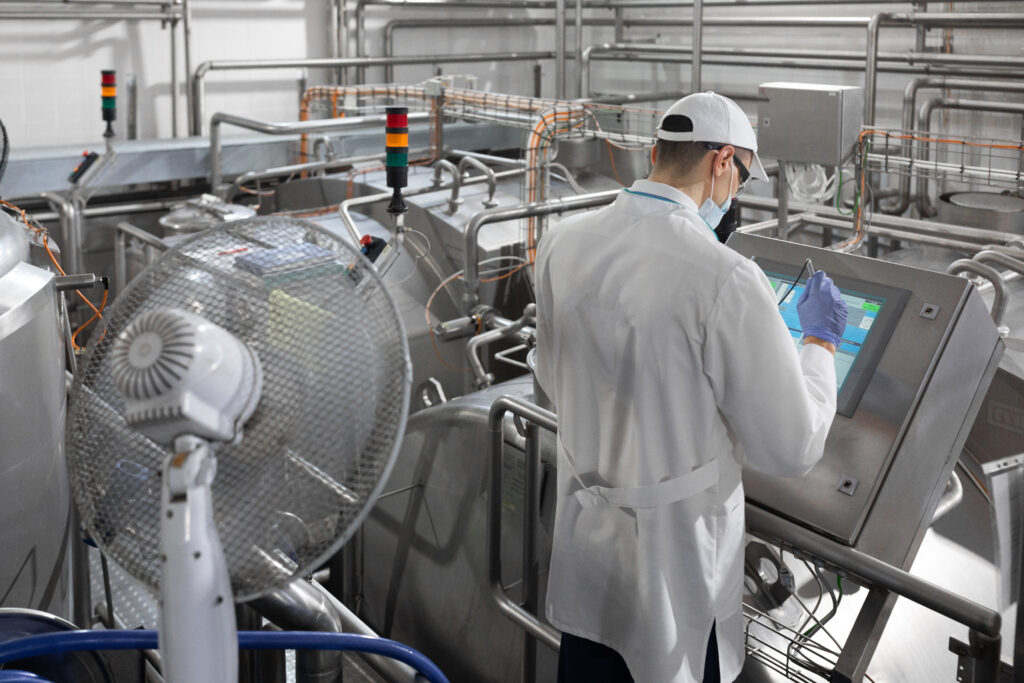 Inspector In A Mask And A Scrub Stands With A Folder Tablet In His Hands At The Dairy Plant